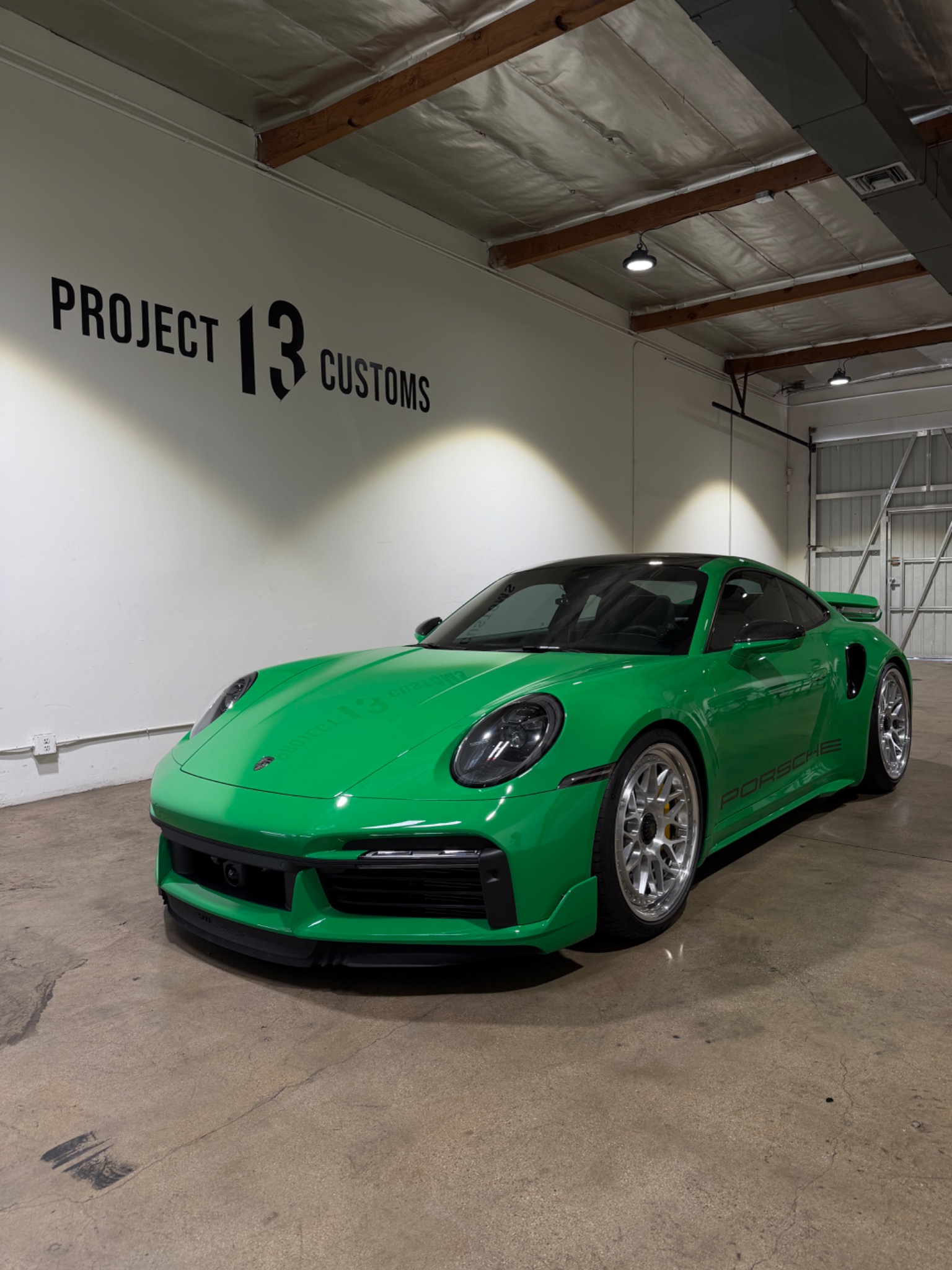 Green Porsche with silver wheels inside Project 13 Customs